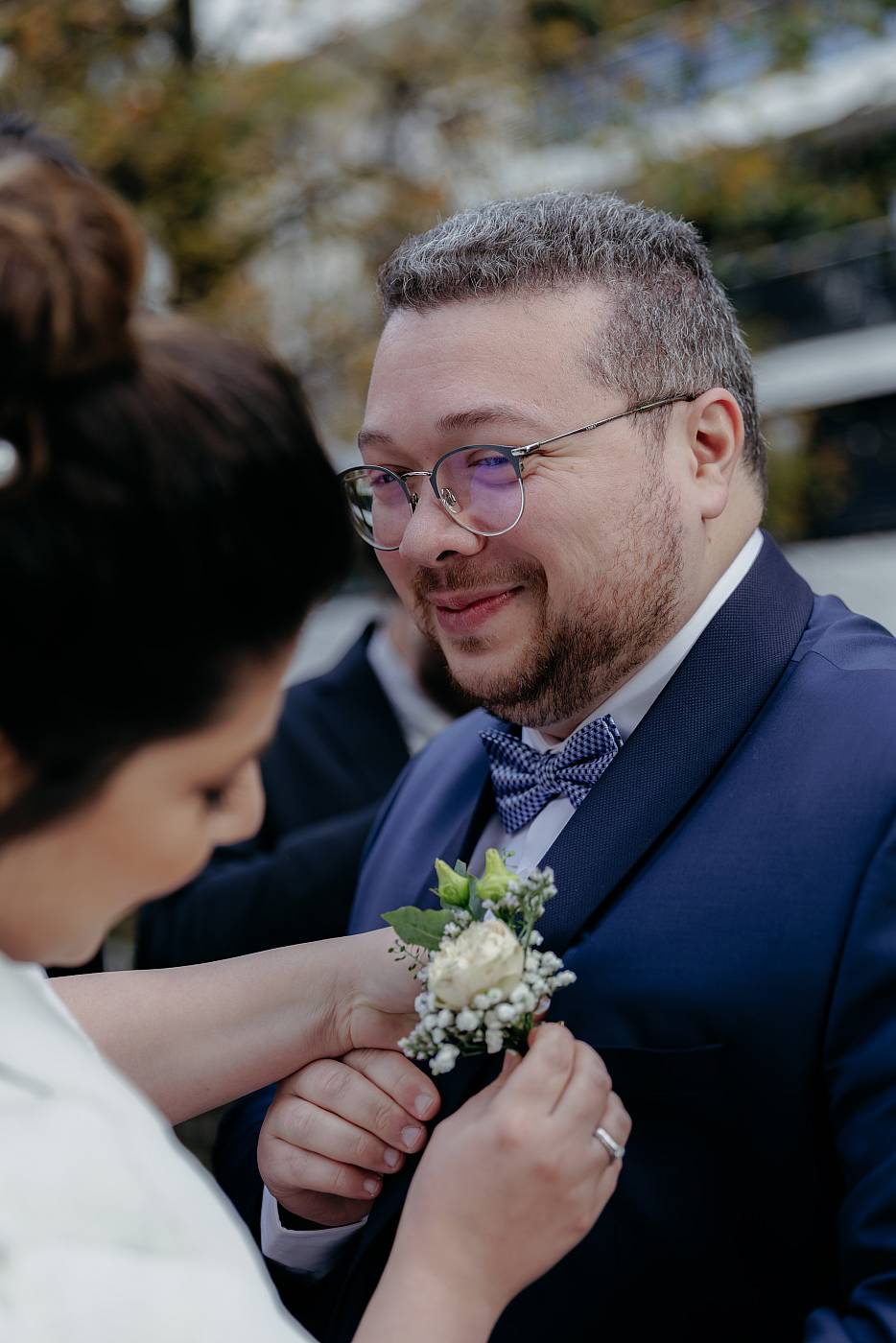 La mariée accroche la mariée sur la poche de costume du marié