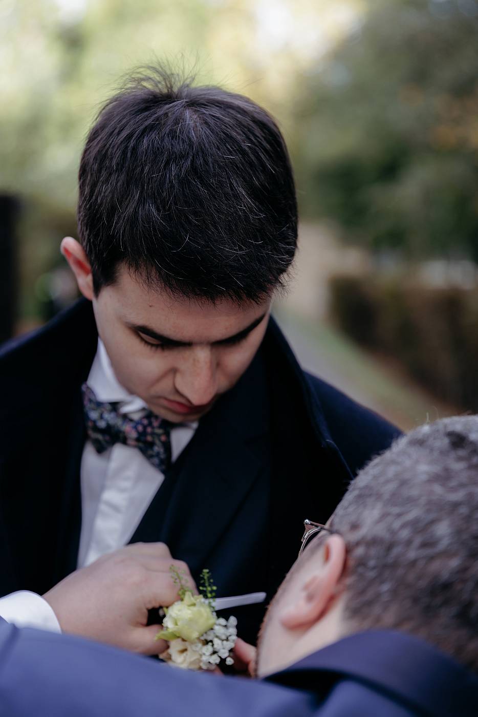 Le marié accroche une fleur sur la poche de costume de son témoin