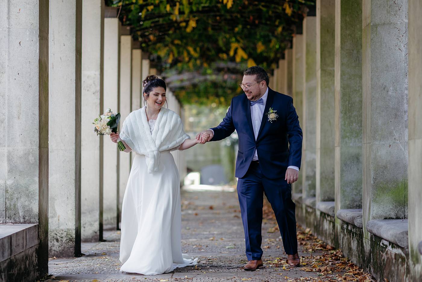 Les mariés main dans la main sous les arcades du parc de Bercy