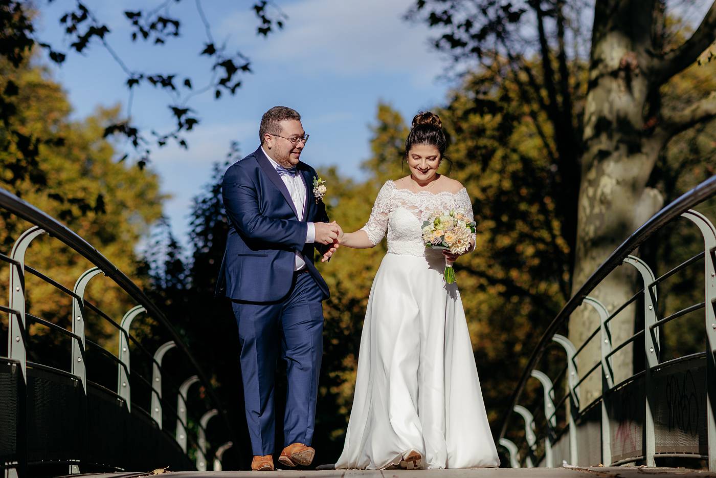 Les mariés marchent main dans la main sur le pont du parc de Bercy