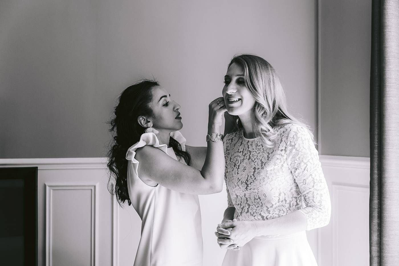 L'ami de la mariée aide la mariée a accrocher ses boucles d'oreilles