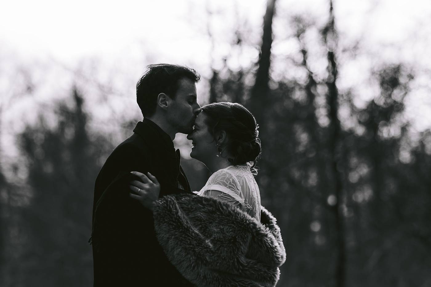 Baiser sur le front de la mariée dans la forêt de Fontainebleau
