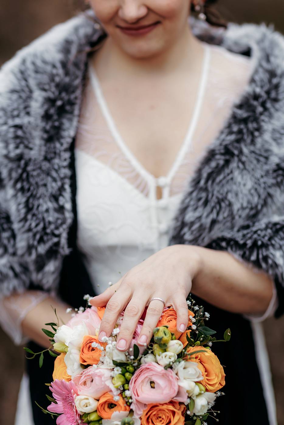 Gros plan sur le bouquet et l'alliance de la mariée