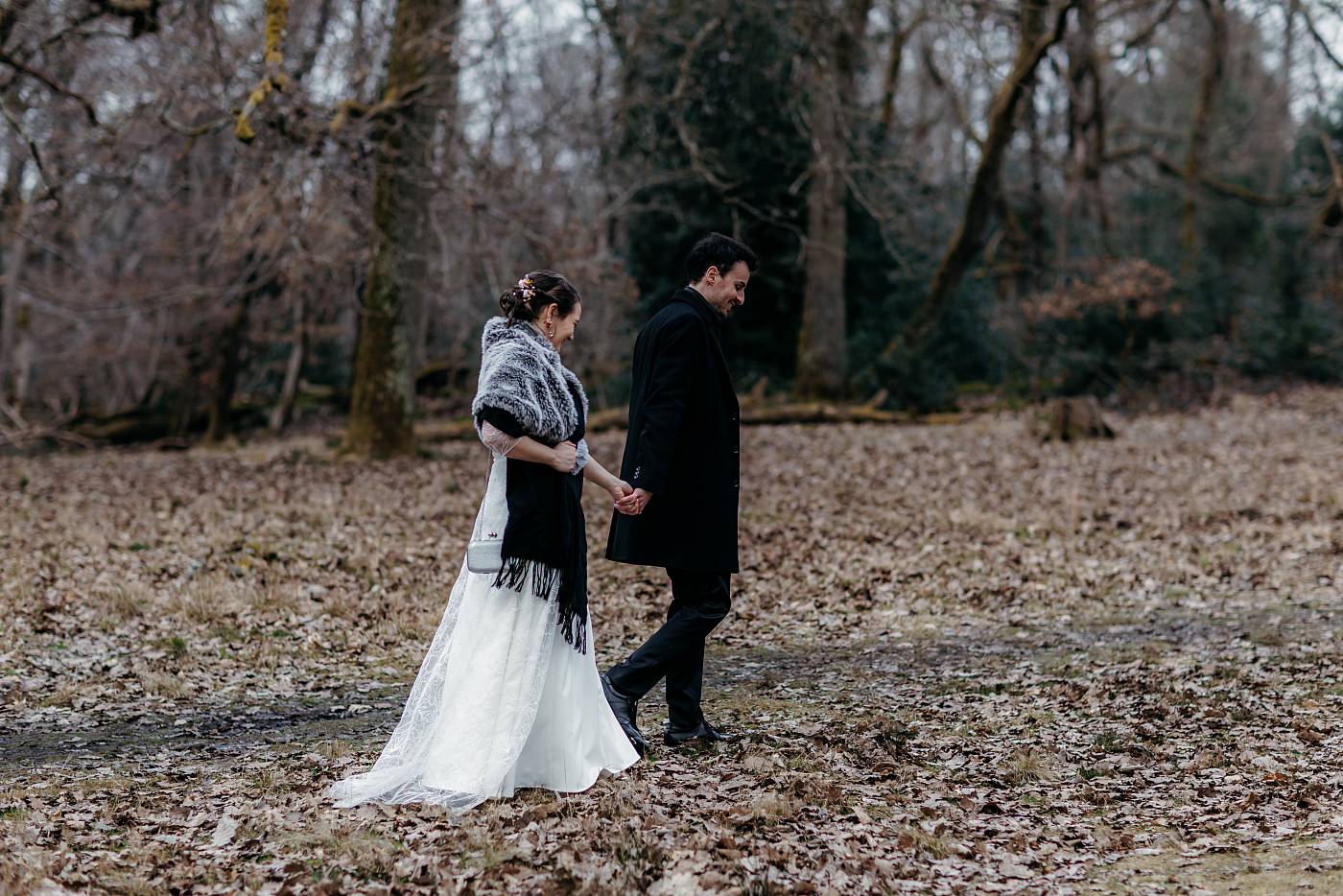 Les mariés marchent main dans la main dans la forêt de Fontainebleau