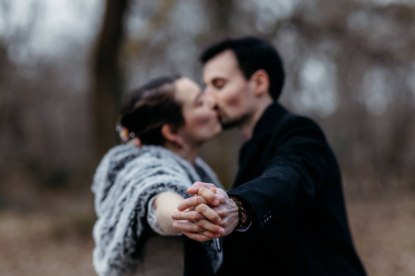 Les mariés s'embrassent en se tenant par la main dans la forêt de Fontainebleau