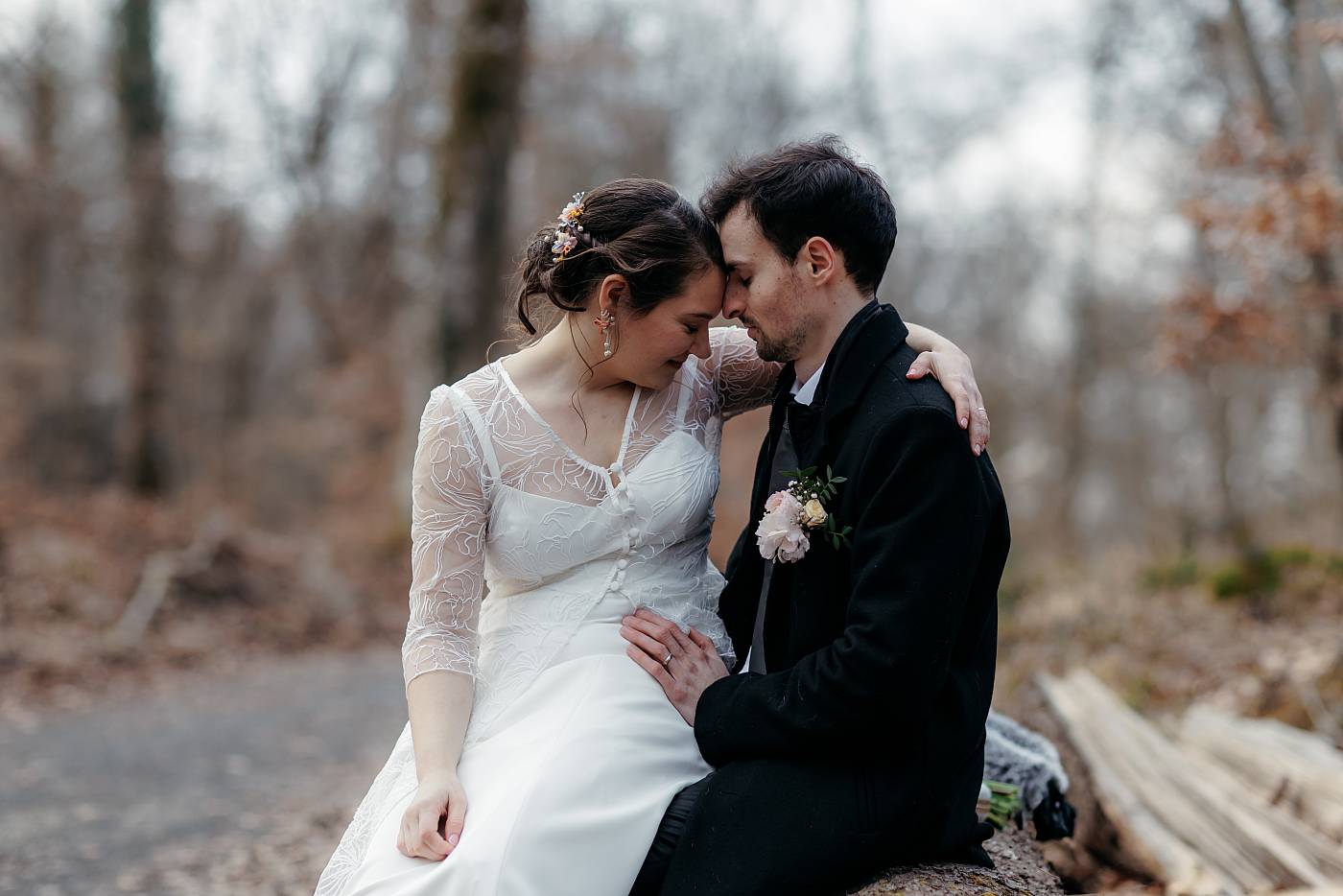Petit moment tendre et romantique entre les mariés assis sur un rondins de bois