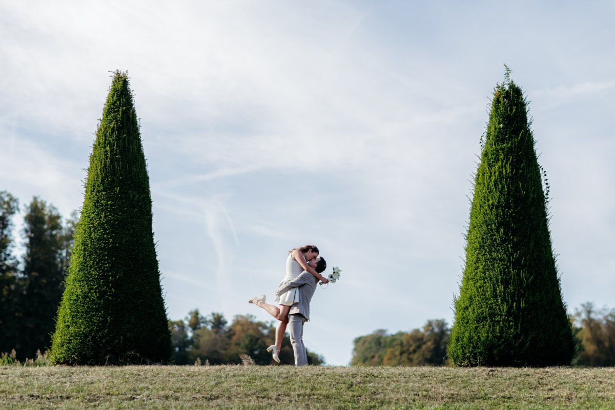 Séance photo de couple : le marié soulève la mariée pour un baiser, entre deux arbres