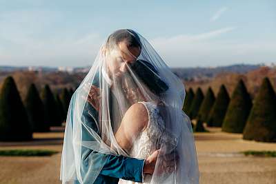 Les mariés enlacés sous leur voile de la mariée