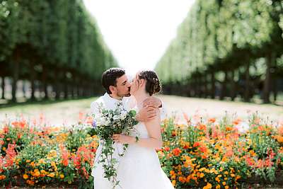 Le baiser des mariés devant un parterre de fleurs