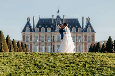 Pose acrobatique des mariés devant le château